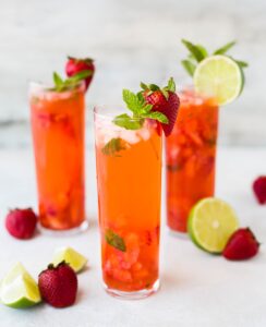 Fersken hindbær-drik med jordbær og mint på kanten af glasset